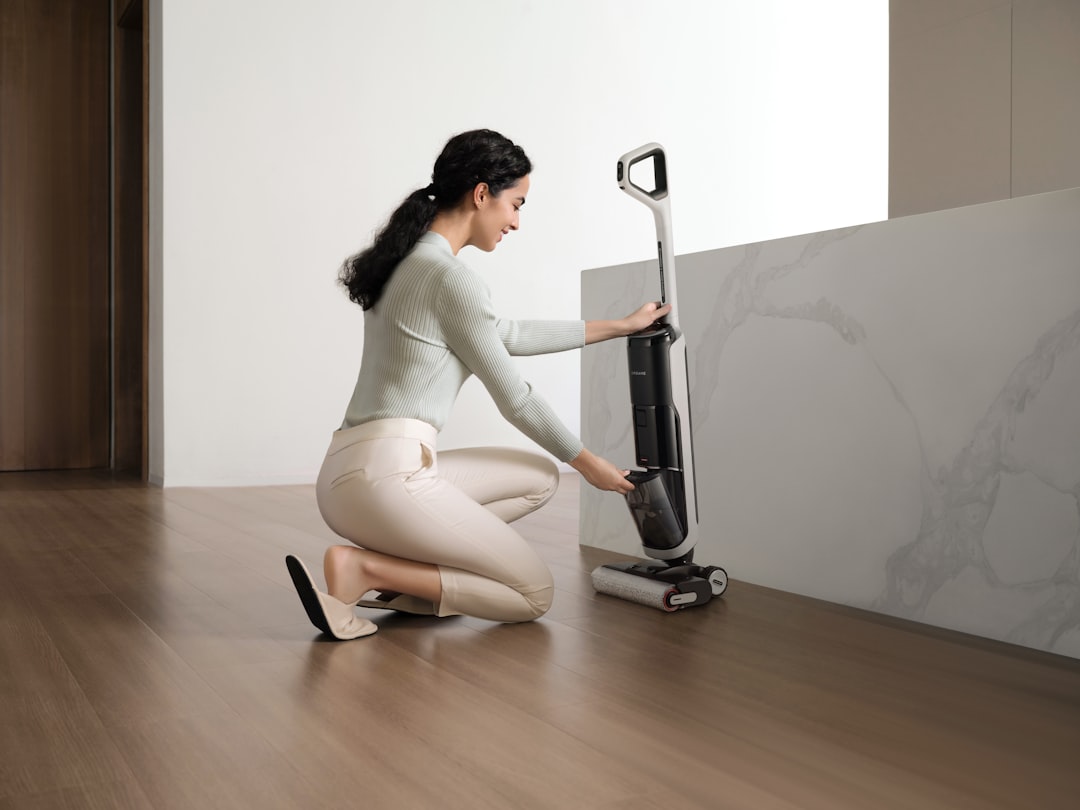 A woman kneels to adjust a Dreame wet dry vacuum by a counter, showing hands on vacuum mop use for everyday floor care.